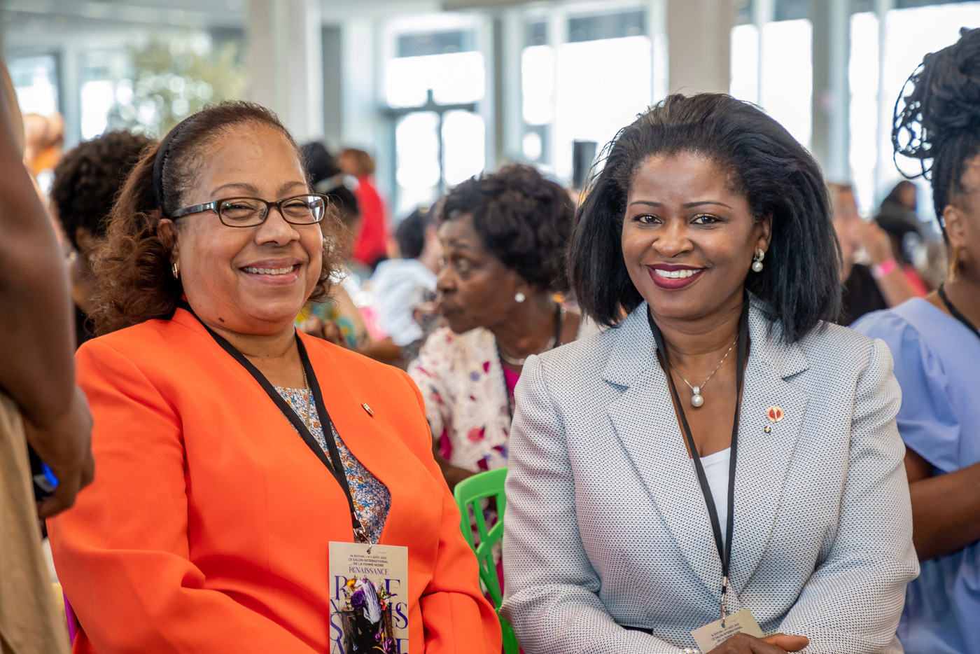 Two women smiling in a crowd at an event