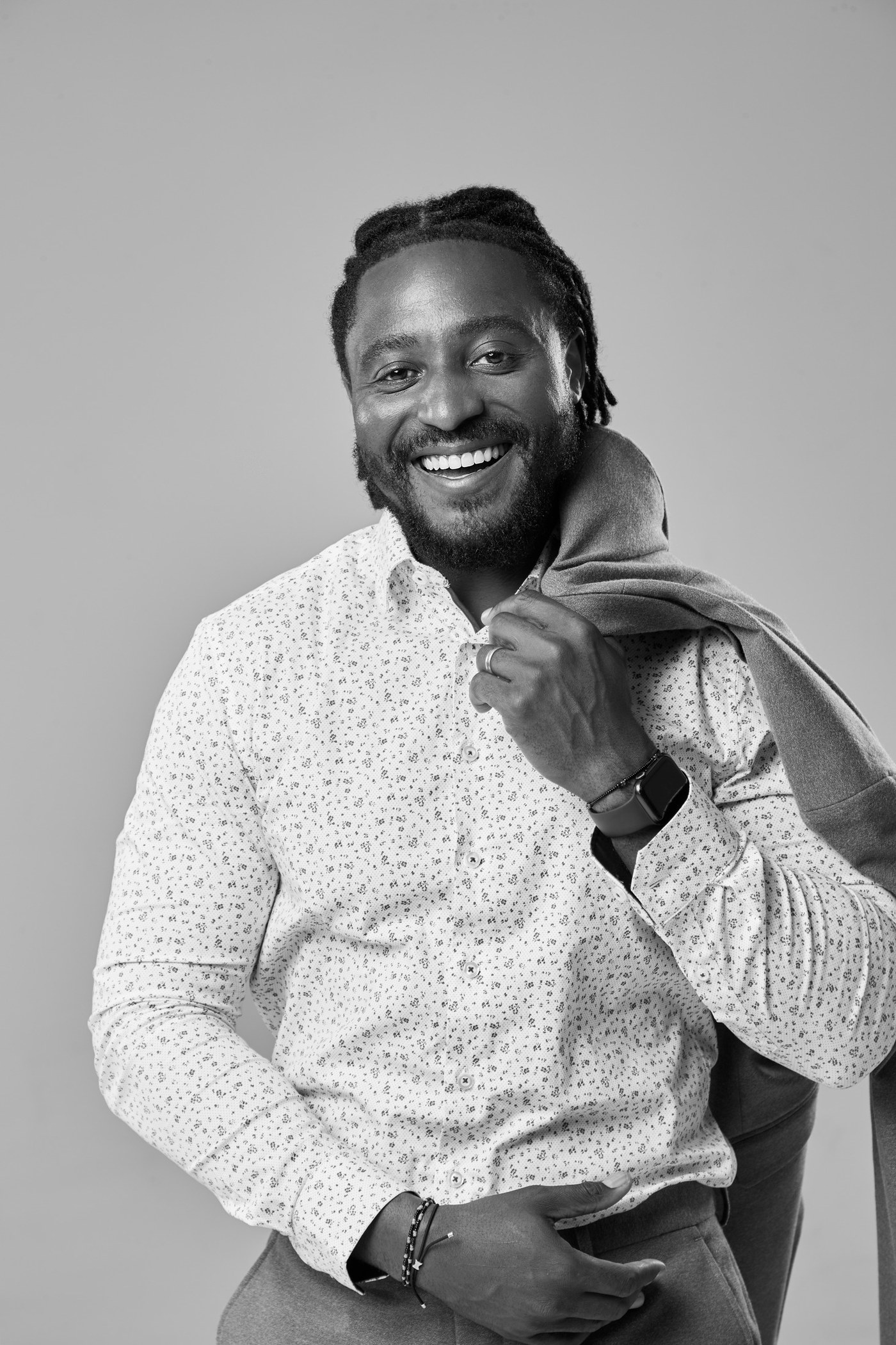 Black and white portrait of a smiling man with a jacket over his shoulder